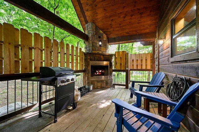 deck featuring an outdoor stone fireplace and area for grilling