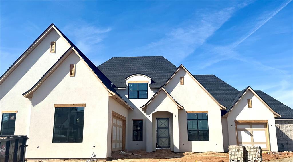 view of front of home with an attached garage, a shingled roof, and stucco siding