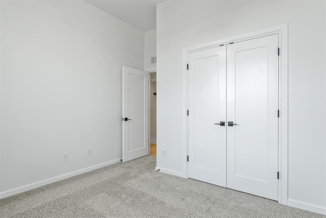 unfurnished bedroom featuring light carpet and a closet