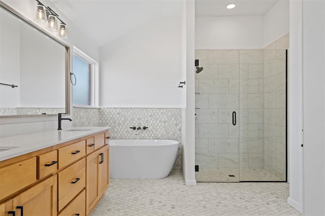 bathroom with plus walk in shower, vanity, tile walls, and tile patterned flooring