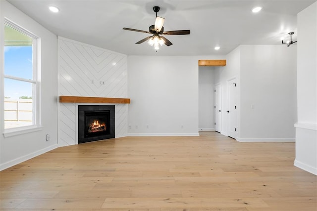 unfurnished living room with a large fireplace, plenty of natural light, and light wood-type flooring