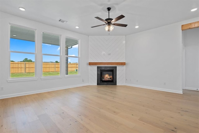 unfurnished living room with ceiling fan, light hardwood / wood-style floors, and a fireplace