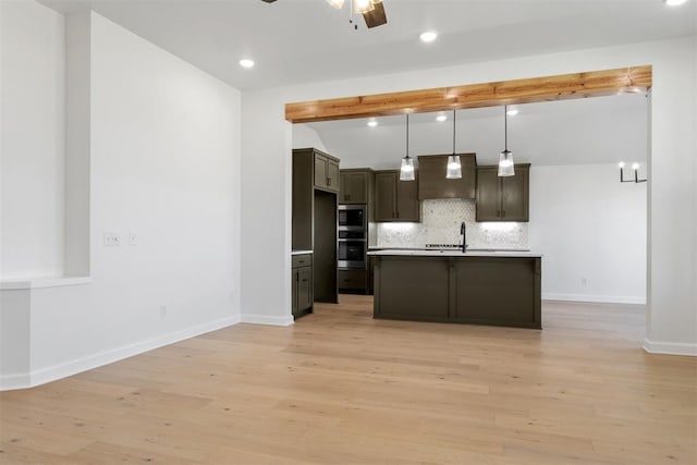 kitchen featuring backsplash, pendant lighting, a center island with sink, custom range hood, and light wood-type flooring