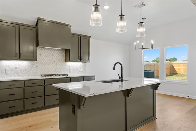 kitchen featuring pendant lighting, sink, stainless steel gas cooktop, and an island with sink