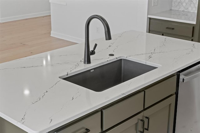 room details with gray cabinetry, dishwasher, sink, light hardwood / wood-style flooring, and light stone countertops