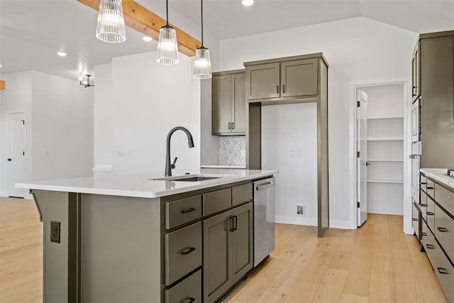 kitchen with sink, hanging light fixtures, light hardwood / wood-style flooring, stainless steel dishwasher, and an island with sink