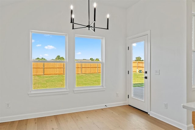 unfurnished dining area with a notable chandelier and light hardwood / wood-style floors