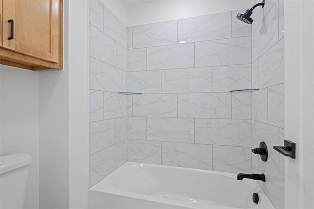 bathroom featuring tiled shower / bath combo and toilet