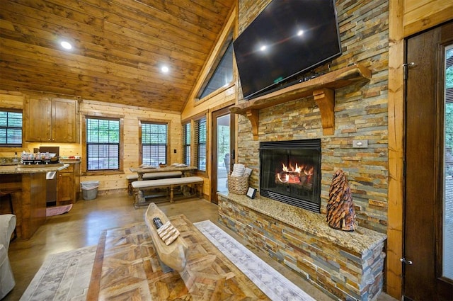 living room with wood walls, a stone fireplace, wood ceiling, and high vaulted ceiling