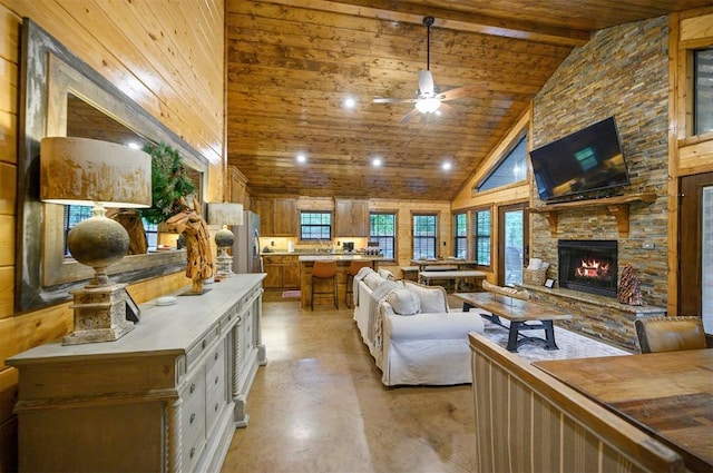 living room featuring ceiling fan, beam ceiling, high vaulted ceiling, wooden ceiling, and a stone fireplace