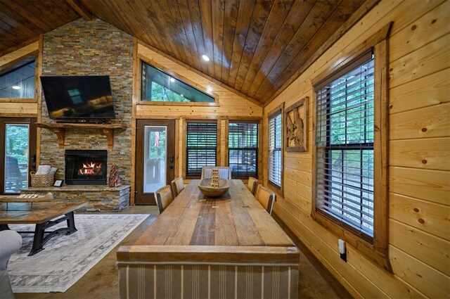 dining room featuring a stone fireplace, wood walls, wood ceiling, and lofted ceiling with beams