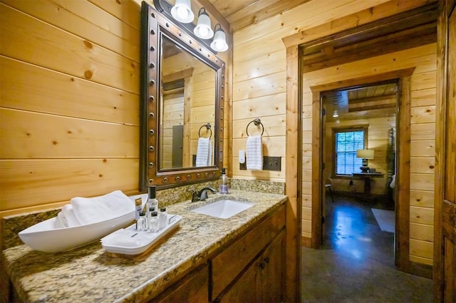 bathroom featuring vanity, wood walls, and concrete flooring