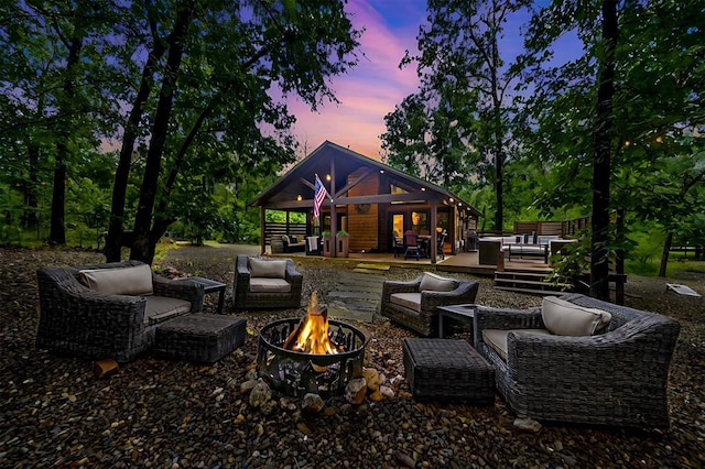 patio terrace at dusk featuring a wooden deck and an outdoor living space with a fire pit