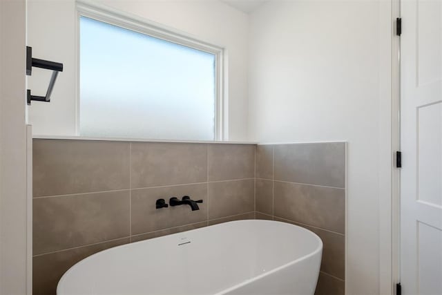 bathroom featuring a bath and tile walls