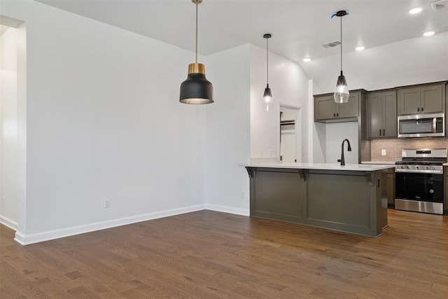 kitchen featuring pendant lighting, lofted ceiling, stainless steel appliances, and dark wood-type flooring