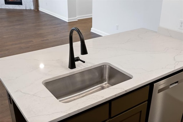 kitchen featuring dishwasher, light stone counters, dark wood-type flooring, and sink