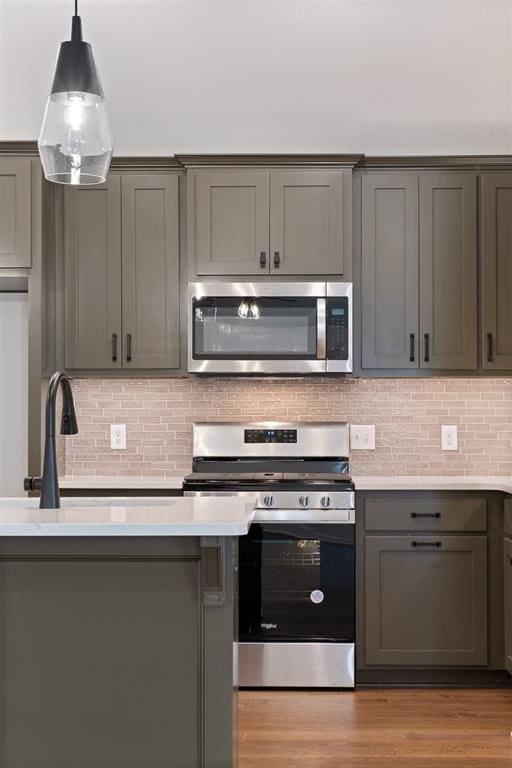 kitchen featuring backsplash, light hardwood / wood-style floors, stainless steel appliances, pendant lighting, and gray cabinets