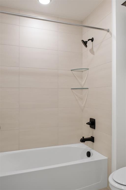 bathroom featuring toilet and tiled shower / bath