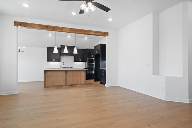 kitchen with premium range hood, ceiling fan, sink, light hardwood / wood-style flooring, and stainless steel microwave