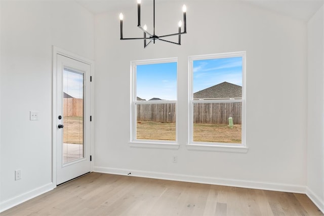 unfurnished dining area featuring a notable chandelier, light hardwood / wood-style floors, and a wealth of natural light