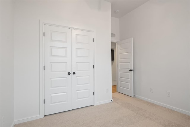 unfurnished bedroom featuring a closet and light colored carpet