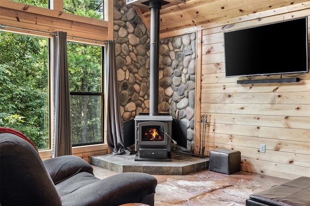 living room with a wood stove, plenty of natural light, and wood walls