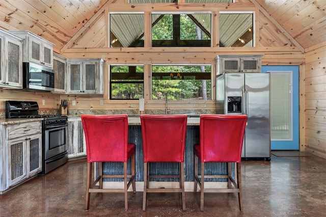 kitchen with wooden ceiling, a center island, stainless steel appliances, and wooden walls