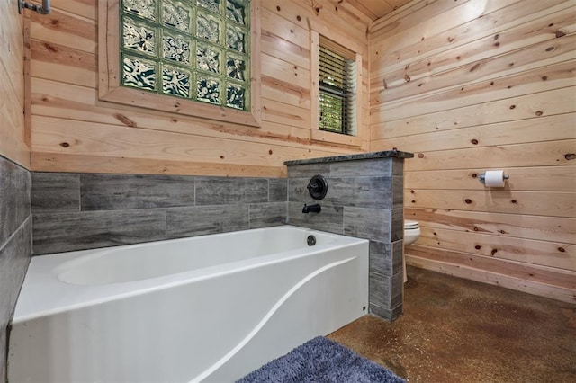 bathroom featuring a tub to relax in, toilet, and wooden walls