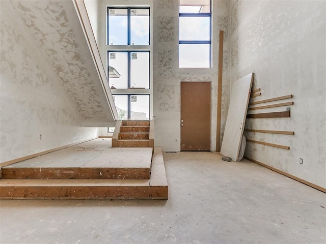 staircase featuring concrete flooring and a towering ceiling