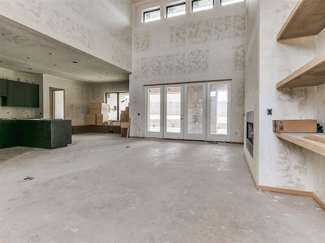 unfurnished living room featuring a towering ceiling and concrete floors