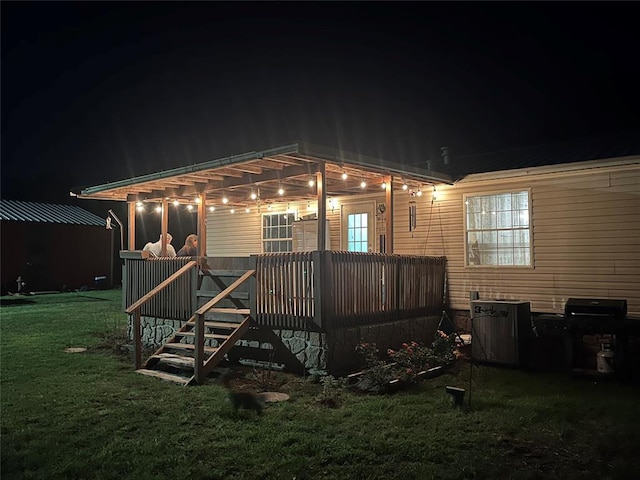 back house at night with a pergola, a deck, and a yard