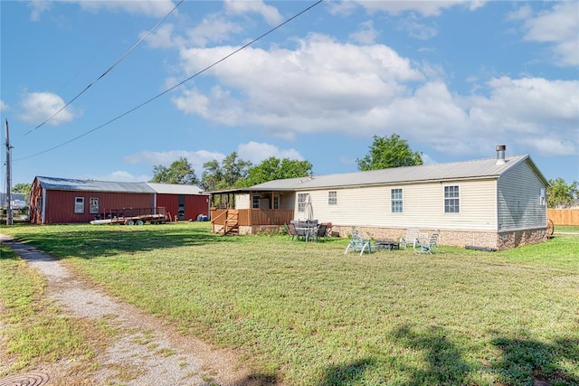 rear view of property featuring a yard and an outdoor structure