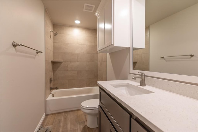 full bathroom featuring hardwood / wood-style flooring, tiled shower / bath combo, toilet, and vanity