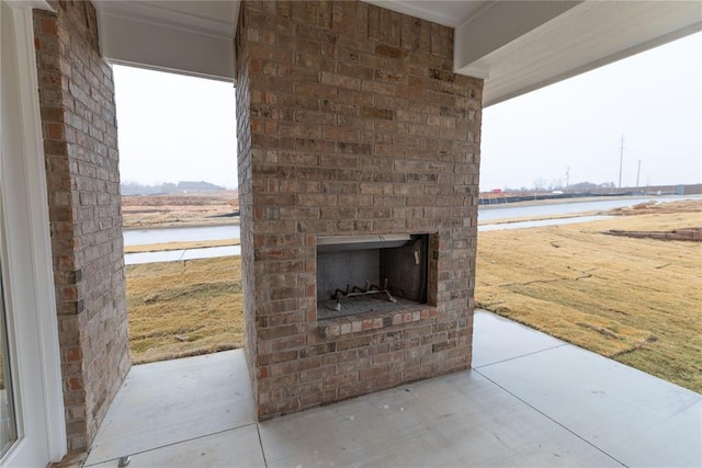 view of patio / terrace featuring a water view and an outdoor brick fireplace