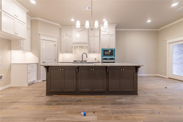 kitchen featuring white cabinetry, black microwave, light hardwood / wood-style flooring, oven, and a center island with sink