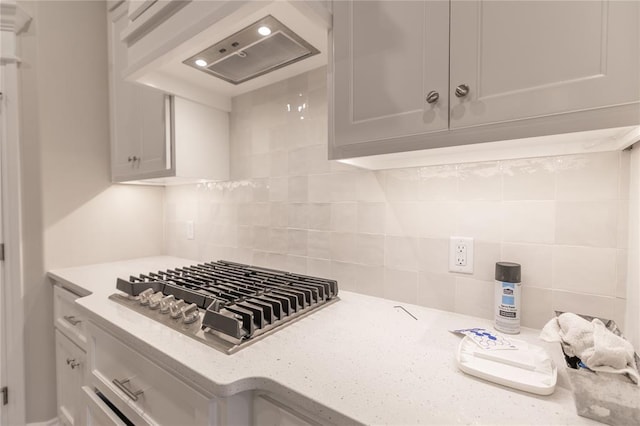 kitchen with backsplash, white cabinets, custom range hood, and stainless steel gas stovetop