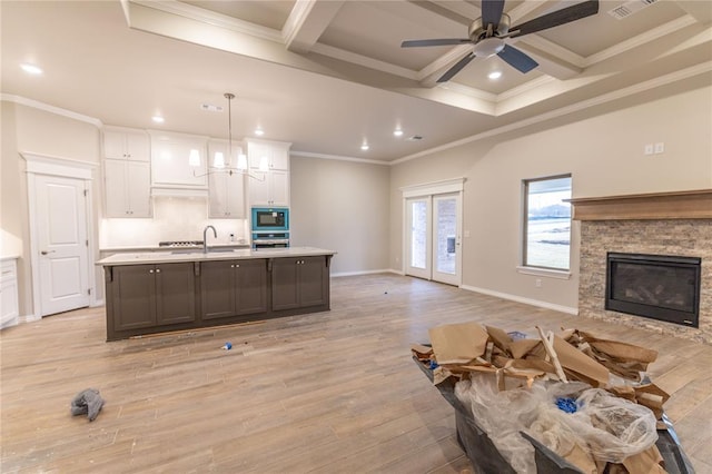 kitchen featuring built in microwave, a spacious island, pendant lighting, light hardwood / wood-style flooring, and white cabinets