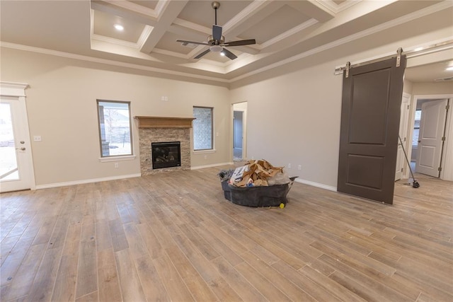 unfurnished living room featuring a barn door, light hardwood / wood-style floors, and a healthy amount of sunlight