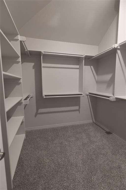 spacious closet with dark carpet and lofted ceiling