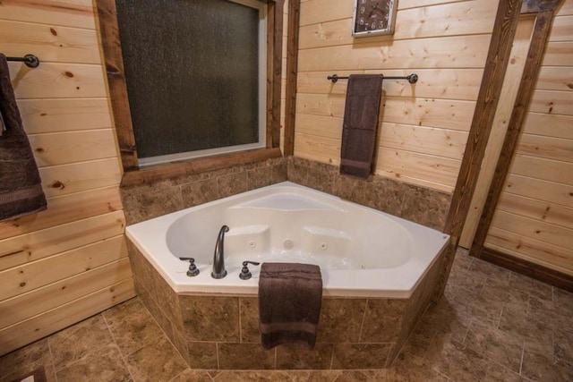 bathroom with tiled bath and wood walls