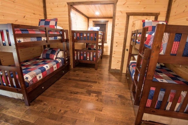 bedroom with dark hardwood / wood-style flooring and wood walls