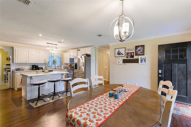 dining area with dark hardwood / wood-style flooring, ornamental molding, and an inviting chandelier