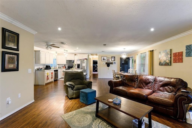 living room featuring hardwood / wood-style floors, ceiling fan, ornamental molding, and a textured ceiling