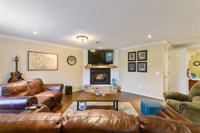 living room with hardwood / wood-style floors, a stone fireplace, and crown molding