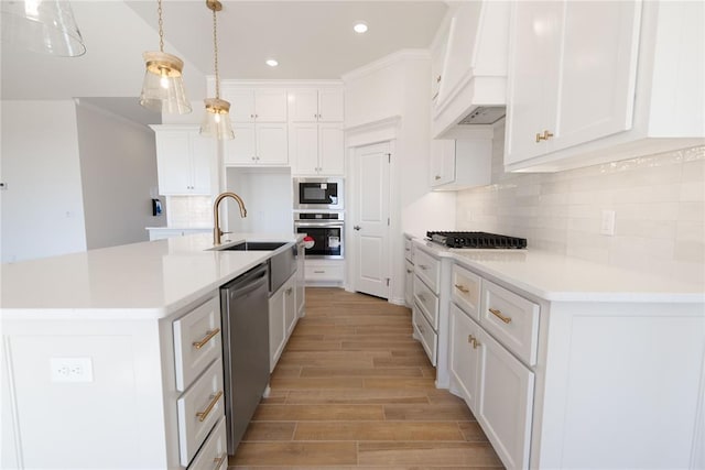 kitchen with white cabinetry, stainless steel appliances, and an island with sink