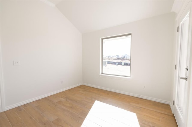 unfurnished room with vaulted ceiling and light wood-type flooring