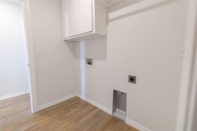 washroom featuring electric dryer hookup, washer hookup, cabinets, and light wood-type flooring