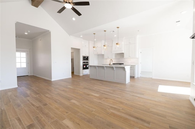 unfurnished living room featuring light wood-type flooring, sink, and high vaulted ceiling