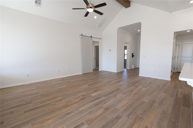 unfurnished living room with beamed ceiling, a barn door, high vaulted ceiling, and ceiling fan