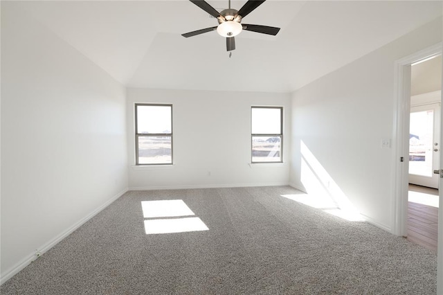 carpeted spare room with a wealth of natural light, ceiling fan, and vaulted ceiling